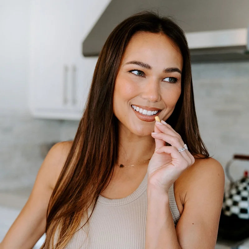 Woman taking her daily capsule in the kitchen